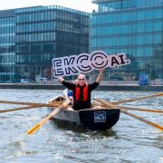 Person in a rowing boat on Dublin’s Grand Canal Dock holding an Ekco AI sign, marking Ekco’s €4 million investment in secure AI adoption, AI governance and cybersecurity solutions for Irish businesses.