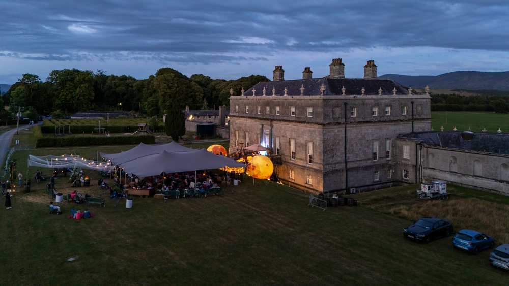 Aerial view of Moonlight Picnic at Russborough House in Wicklow, showcasing glowing moon sculptures, outdoor concert tents and guests enjoying a unique heritage event at sunset.