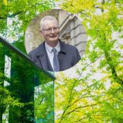 Composite image showing a corporate office building surrounded by green trees and sustainability-focused architecture, alongside a portrait of a business leader, illustrating Chambers Ireland's call for climate infrastructure investment and faster delivery of renewable energy projects in Ireland.