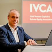 Senior venture capital executive seated at a conference table with a laptop, following election as chairperson of the Irish Venture Capital and Private Equity Association (IVCA), advocating increased investment in Irish start-ups and SMEs.