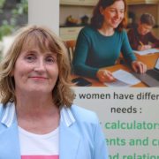 Deirdre McCarthy of FLIT Financial Wellness standing in front of a financial literacy display promoting financial education and money management support for women with caring responsibilities in Ireland.