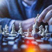 Chess player moving a white king piece on a chessboard, illustrating strategic decision-making, leadership and AI strategy.