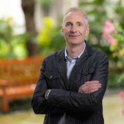 Portrait of a business executive standing outdoors in a garden setting.