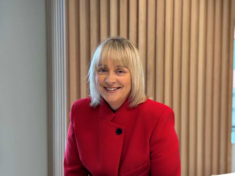 Business leader in a red jacket pictured in a modern office, representing SME growth, business finance and investment in Ireland.