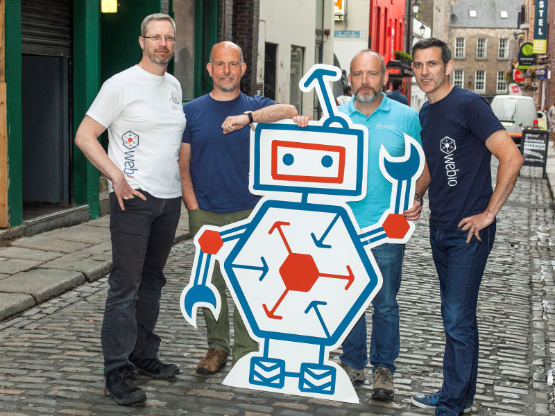 Group of men standing with a robot cut-out on a street in Dublin.