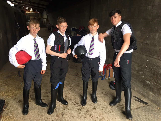 Four young boys dressed in horse-riding gear.