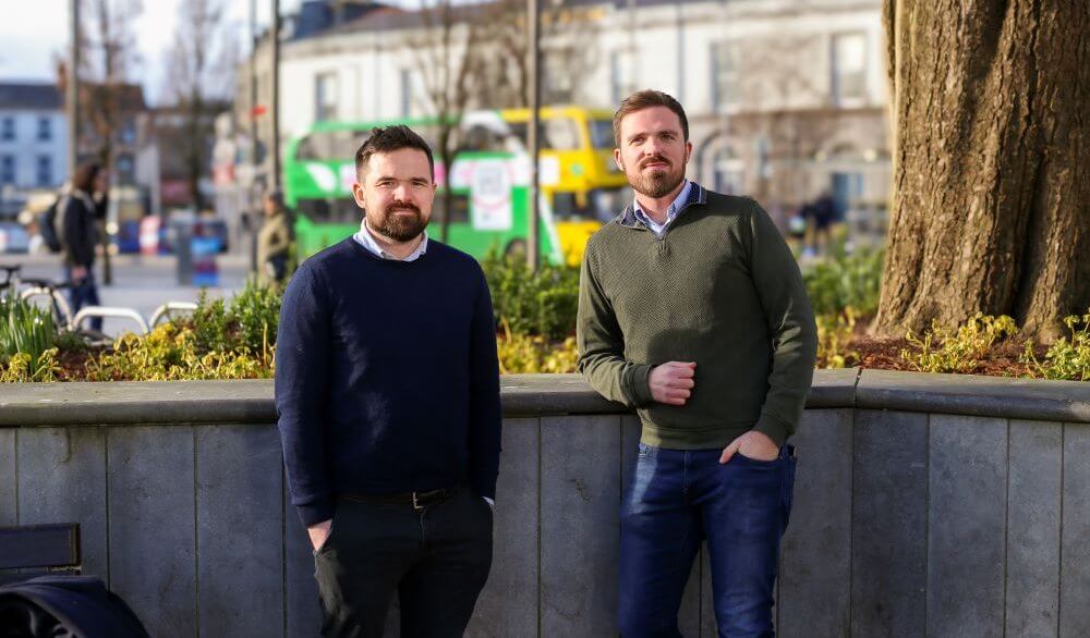 Two men with a bus in the background.