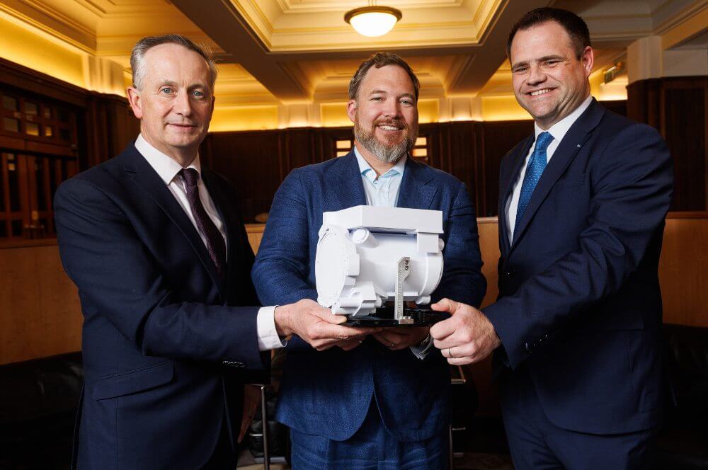 Three men hold a space tech device.