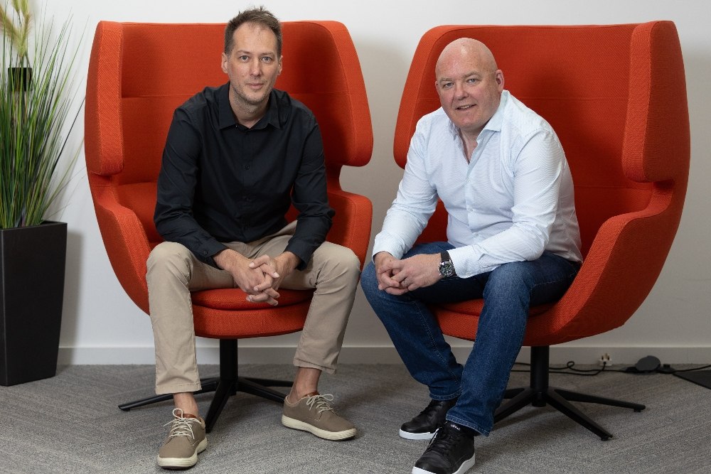 Two men sitting in orange chairs.