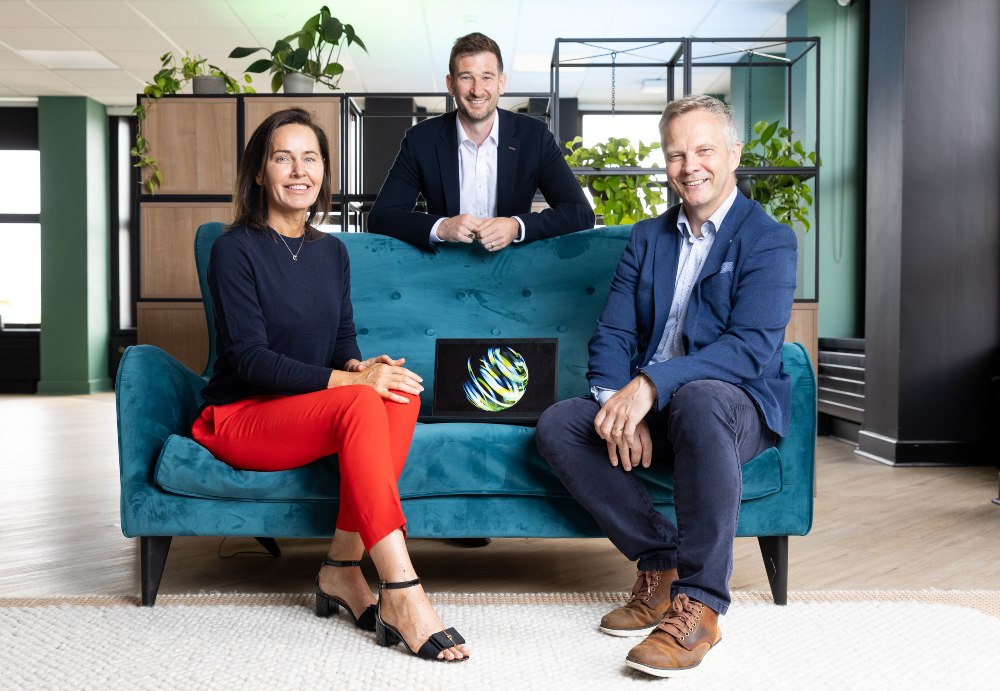 Woman and two men sitting around a blue couch.