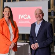 Woman in orange jacket beside man in navy suit.