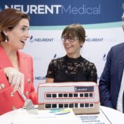 Woman cutting a cake beside man and woman.