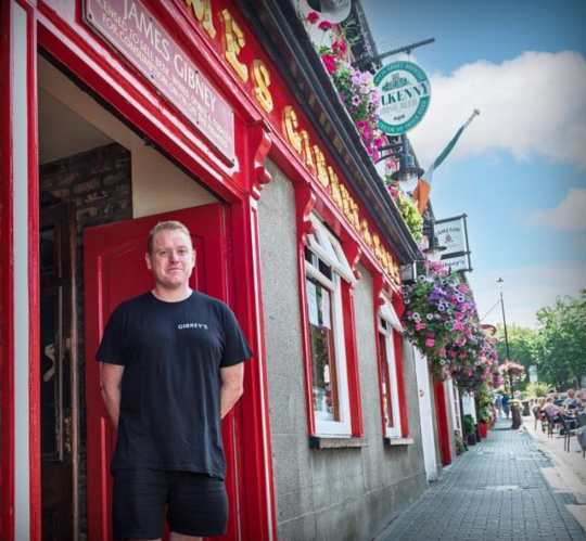 Man in black t-shirt outside a pub in Malahide.