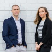 Man and woman standing in front of a wall.